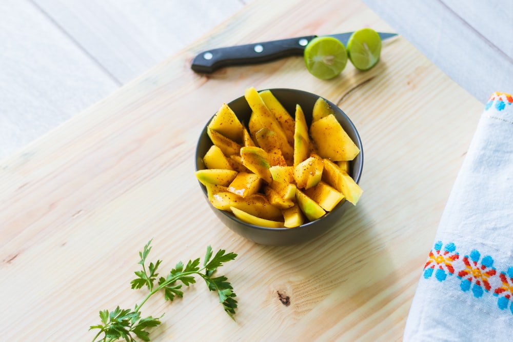 sliced fruits in bowl on wooden chopping board