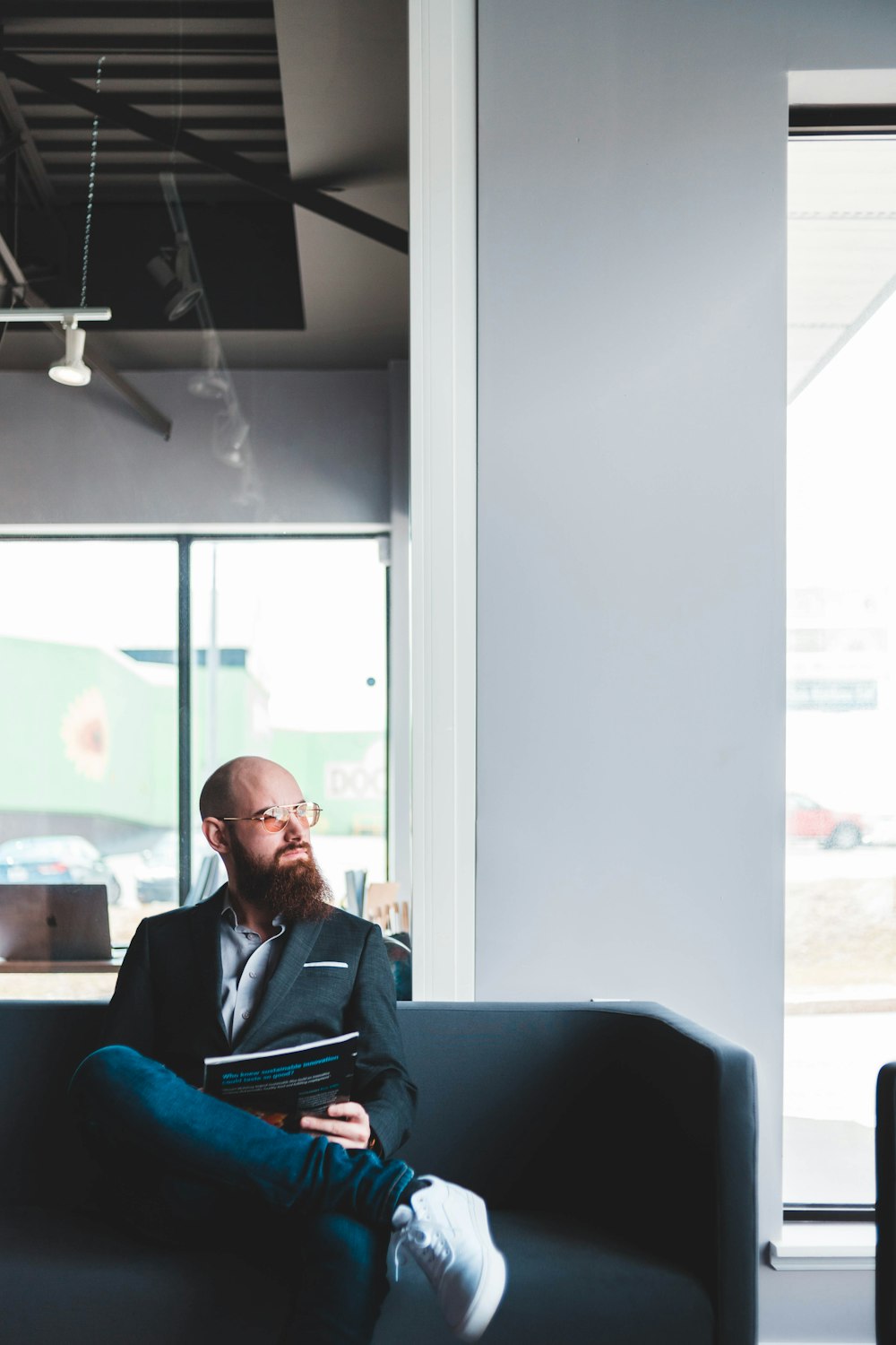 man sitting on sofa holding book and looking at his left