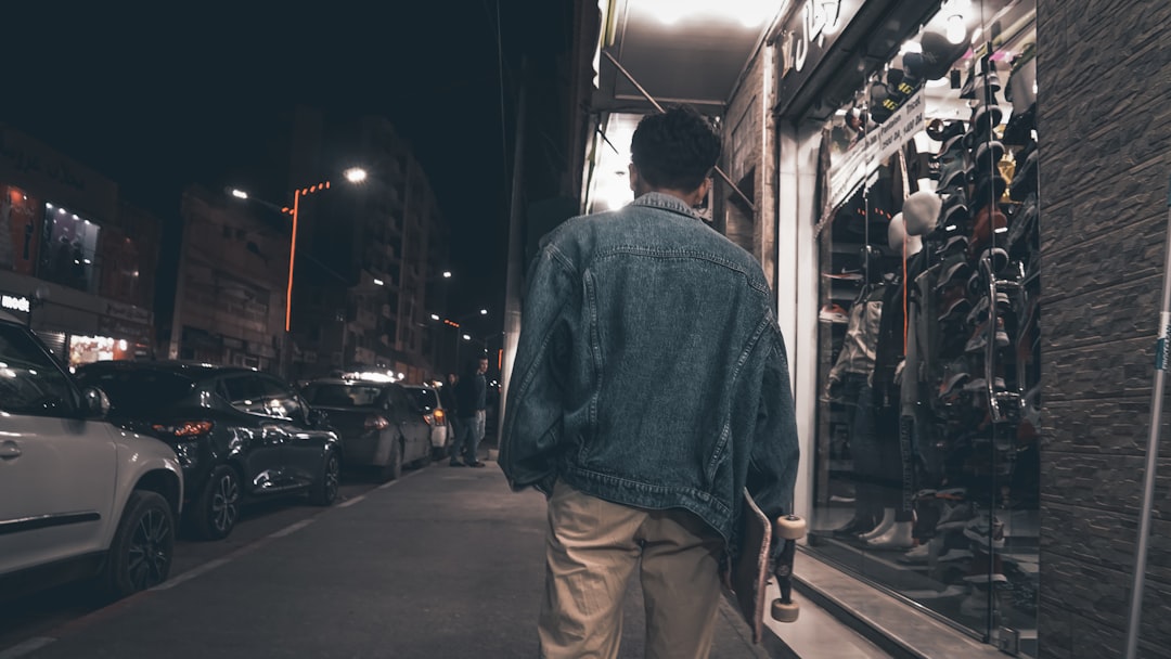 man holding skateboard and walking near building