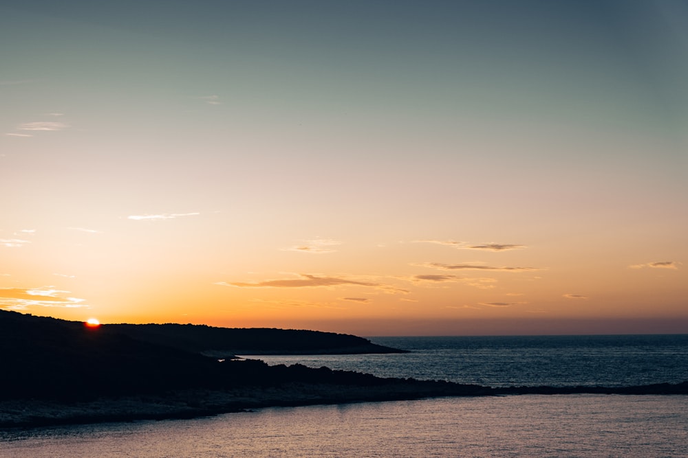 silhouette de montagne au bord de la mer pendant l’heure dorée