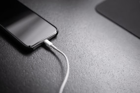 black smartphone with charger cord connected