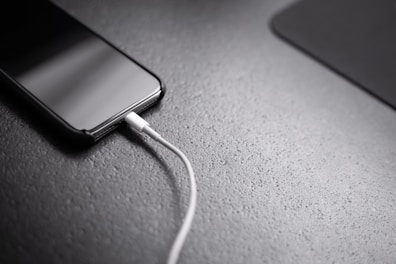 black smartphone with charger cord connected