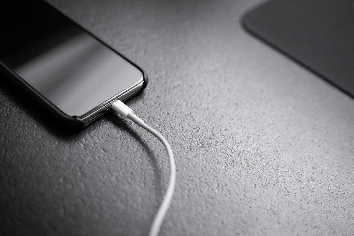 Smartphone plugged into a charging cable on a dark surface