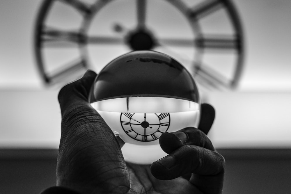 Fotografía en escala de grises de una persona sosteniendo una bola de cristal