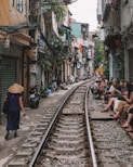 house near train track with people sitting at the side