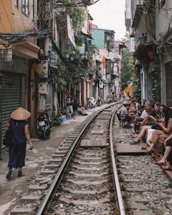 house near train track with people sitting at the side