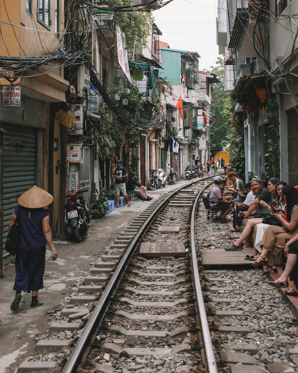 casa perto da linha do trem com pessoas sentadas ao lado