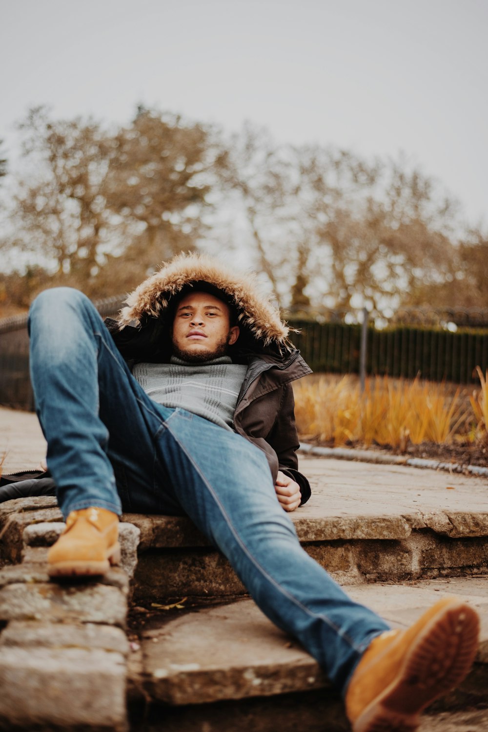 man wearing parka lying on rock