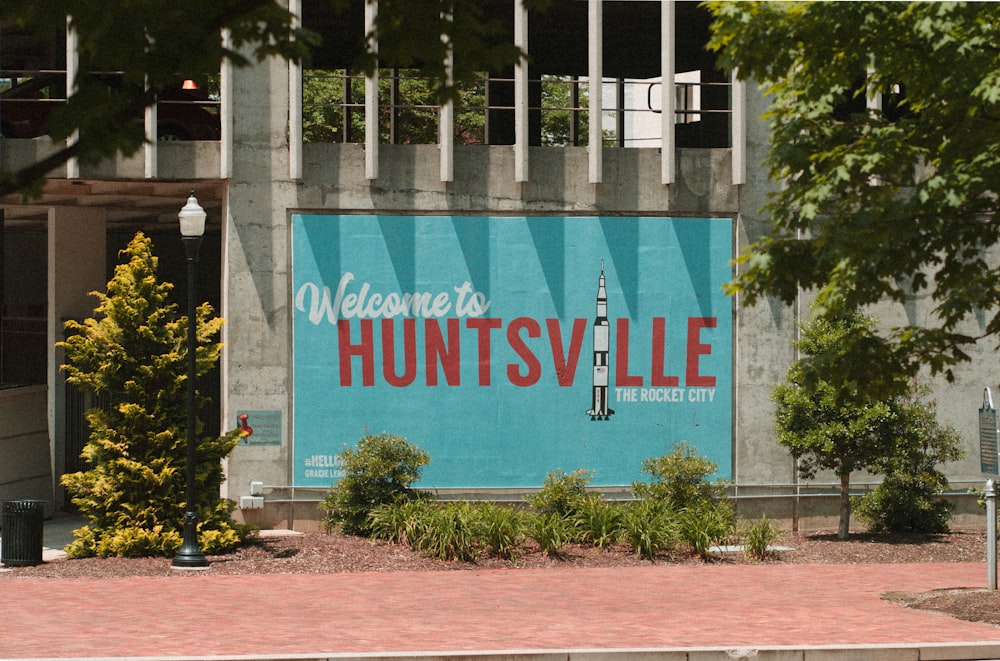 Willkommen in Huntsville Schild an der Wand in der Nähe von Bäumen und Laternenpfahl