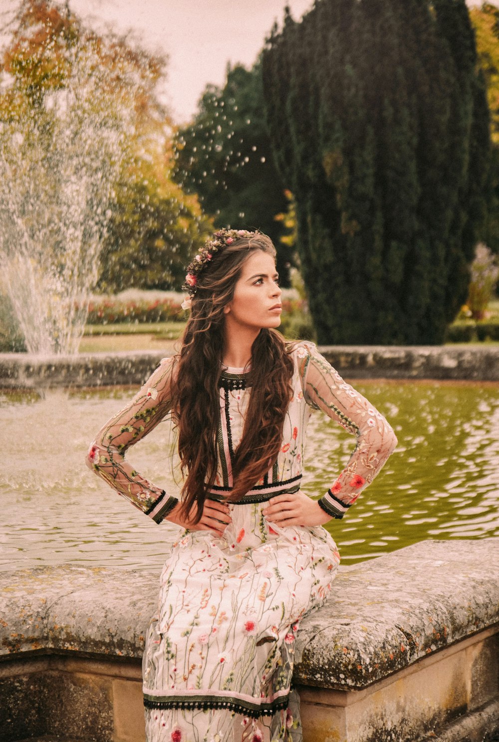 woman sitting on water fountain at daytime