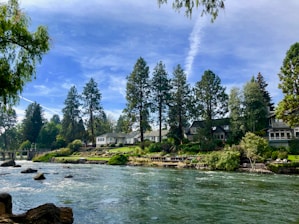 A peaceful river flowing gently beside a cluster of elegant, nature-inspired homes.