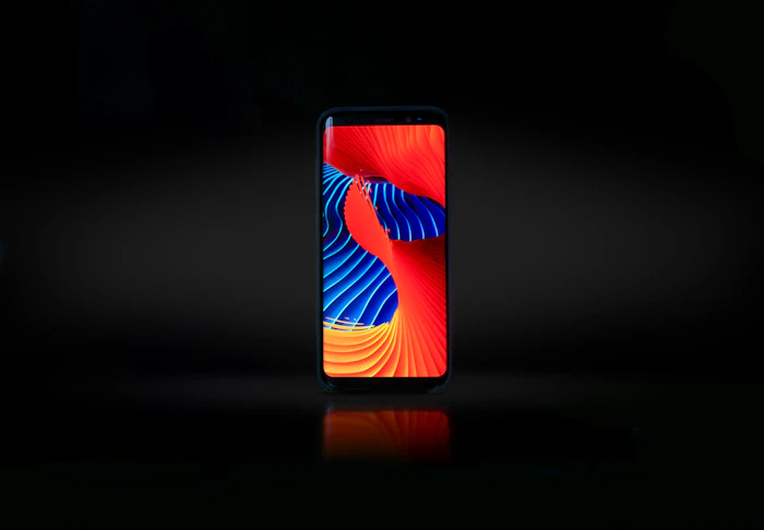 Black smartphone with a colourful wallpaper on a dark background