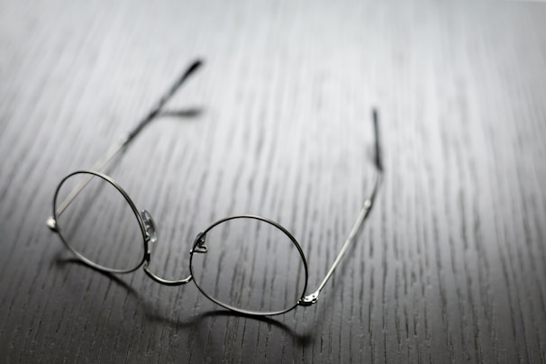 grey framed eyeglasses on wooden surface