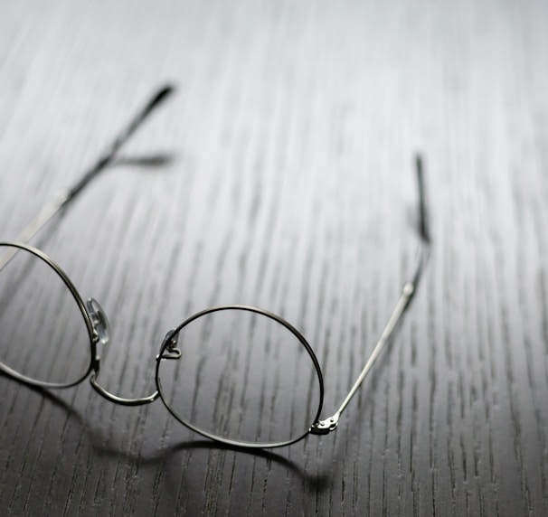 grey framed eyeglasses on wooden surface