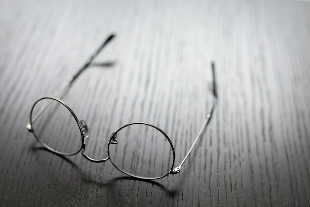 lunettes à monture grise sur surface en bois