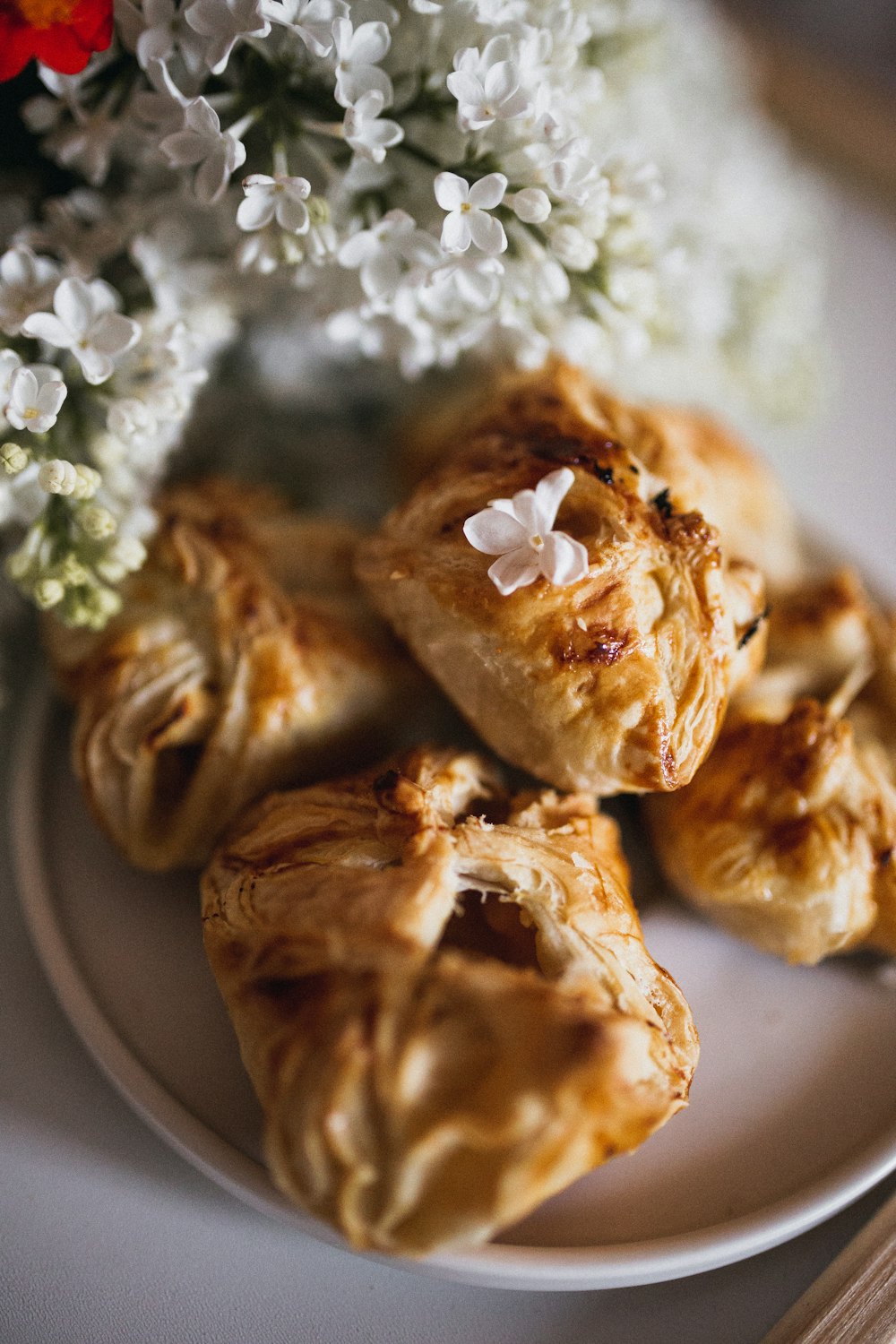 brown pastries on plated beside white flowers