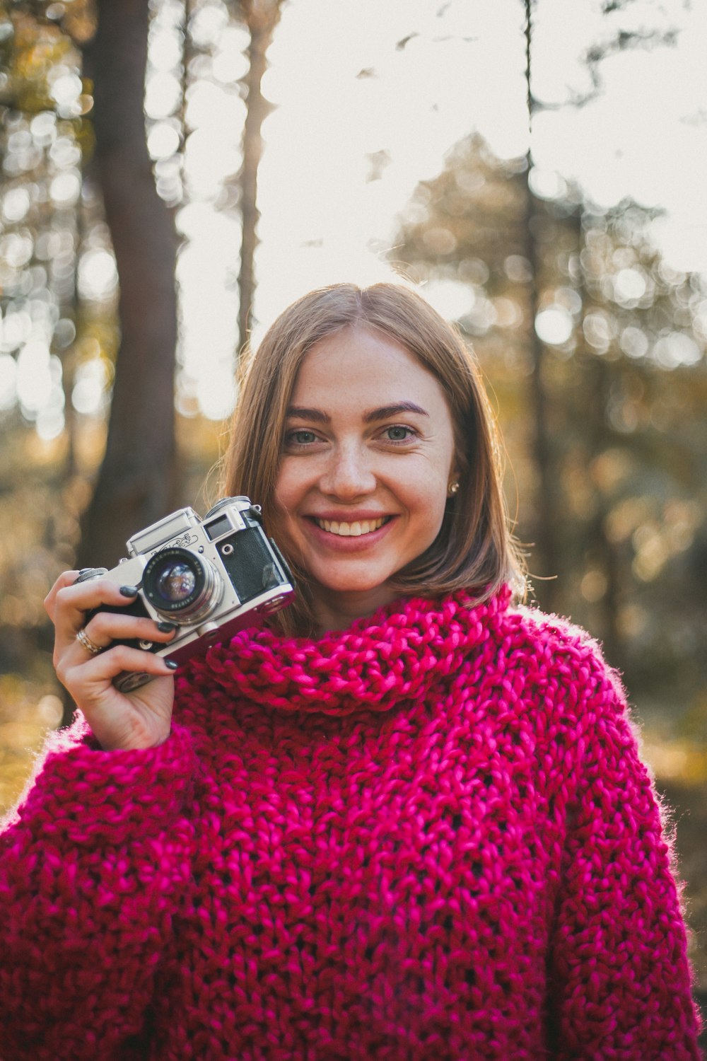 mujer de pie y sonriendo mientras sostiene la cámara