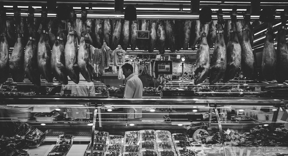 grayscale photography of man standing in store