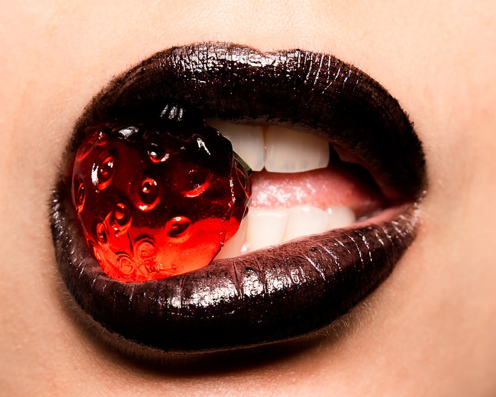 mujer mordiendo caramelo de fresa roja