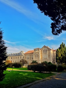 Historic stone lodge building surrounded by lush gardens under a clear sky.