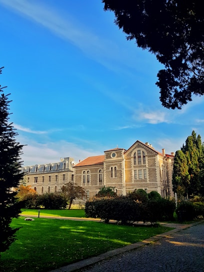 Historic stone lodge building surrounded by lush gardens under a clear sky.