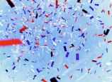 A festive banner with colorful balloons and confetti.