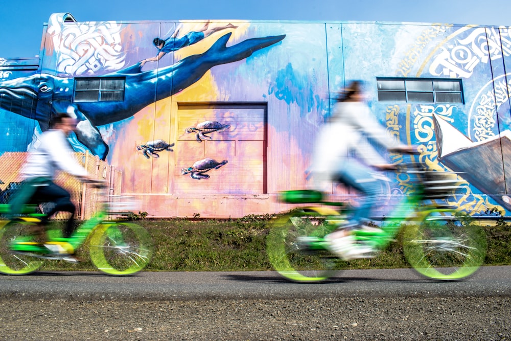 two people riding green bicycles