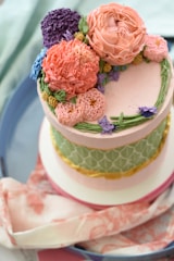 A beautifully decorated pink and purple themed cake topped with fresh berries and delicate icing flowers.