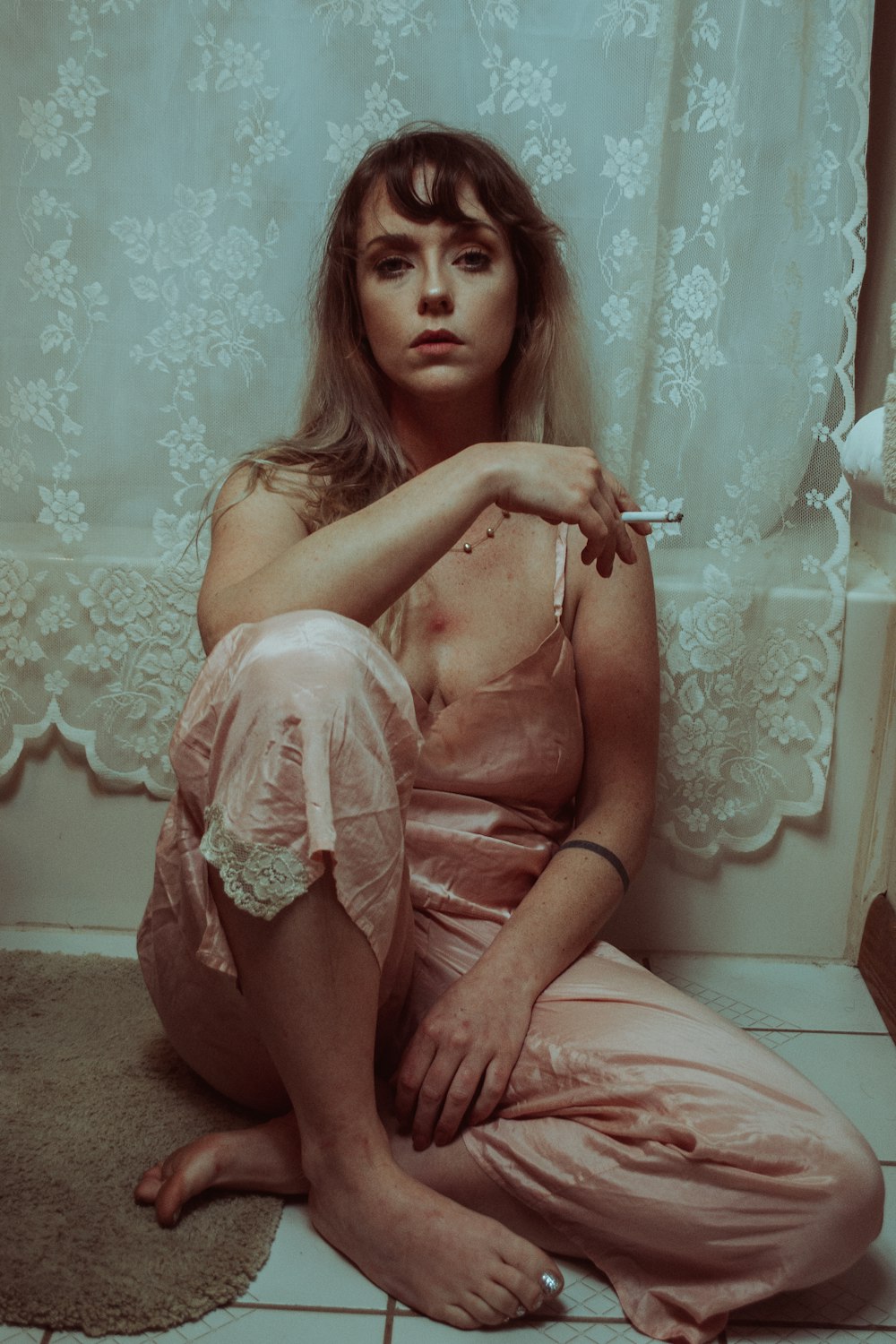 smoking woman seated near curtain