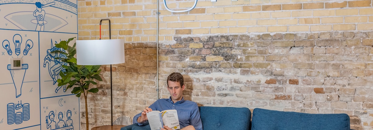 man sitting on blue sofa while reading book