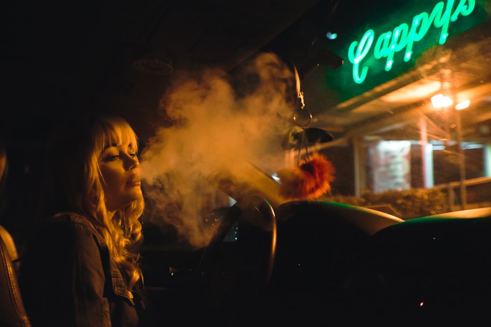 smoking woman near green LED sign