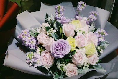 A vibrant bouquet of pastel lilac and pink roses arranged elegantly in a rounded vase.