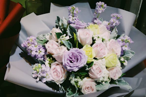 Elegant hand-tied bouquet with pastel roses and eucalyptus leaves, styled for a gift.