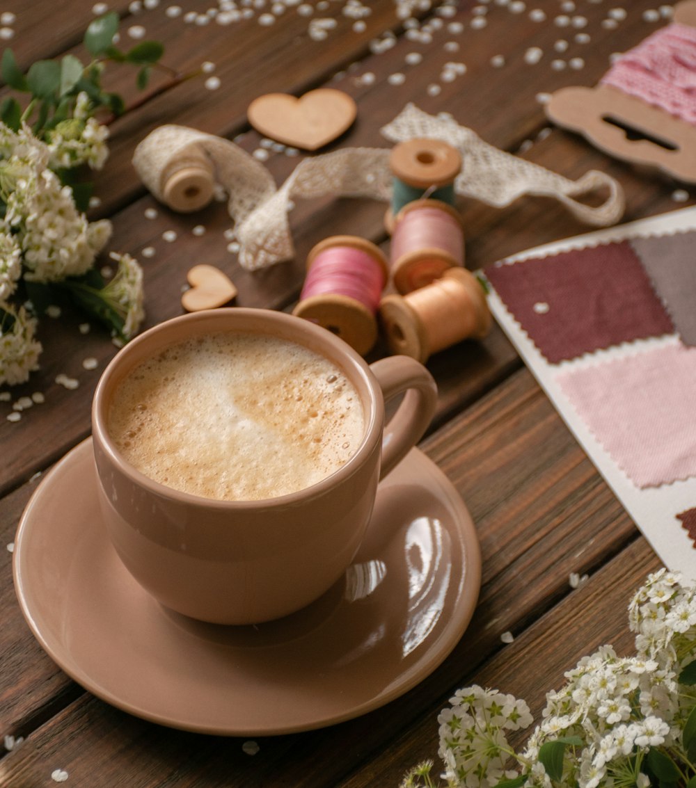 cappuccino in beige mug beside thread spools