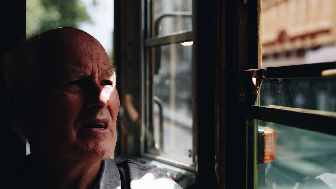 man in grey shirt looking out glass window