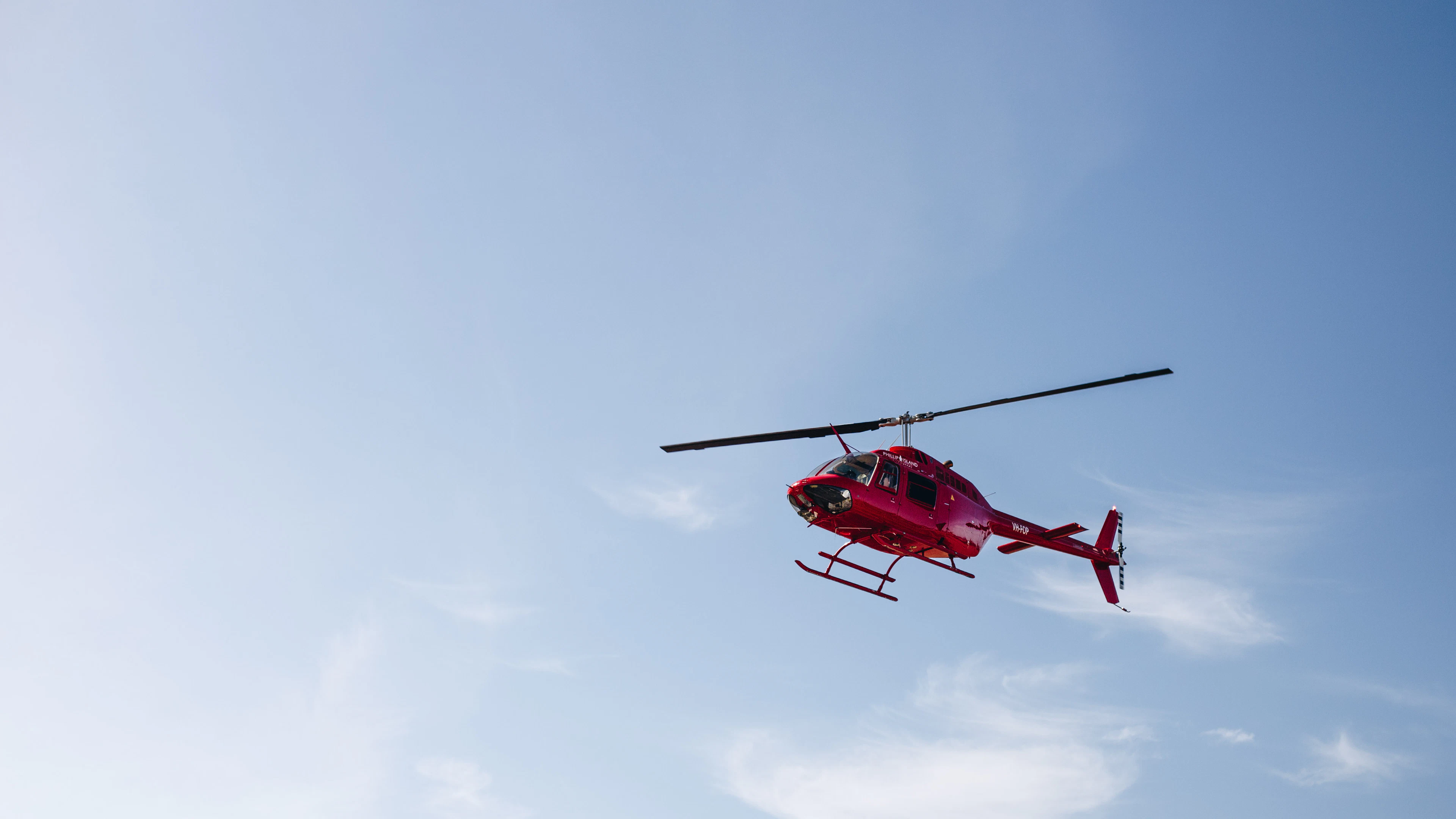 Red helicopter flying against a clear blue sky