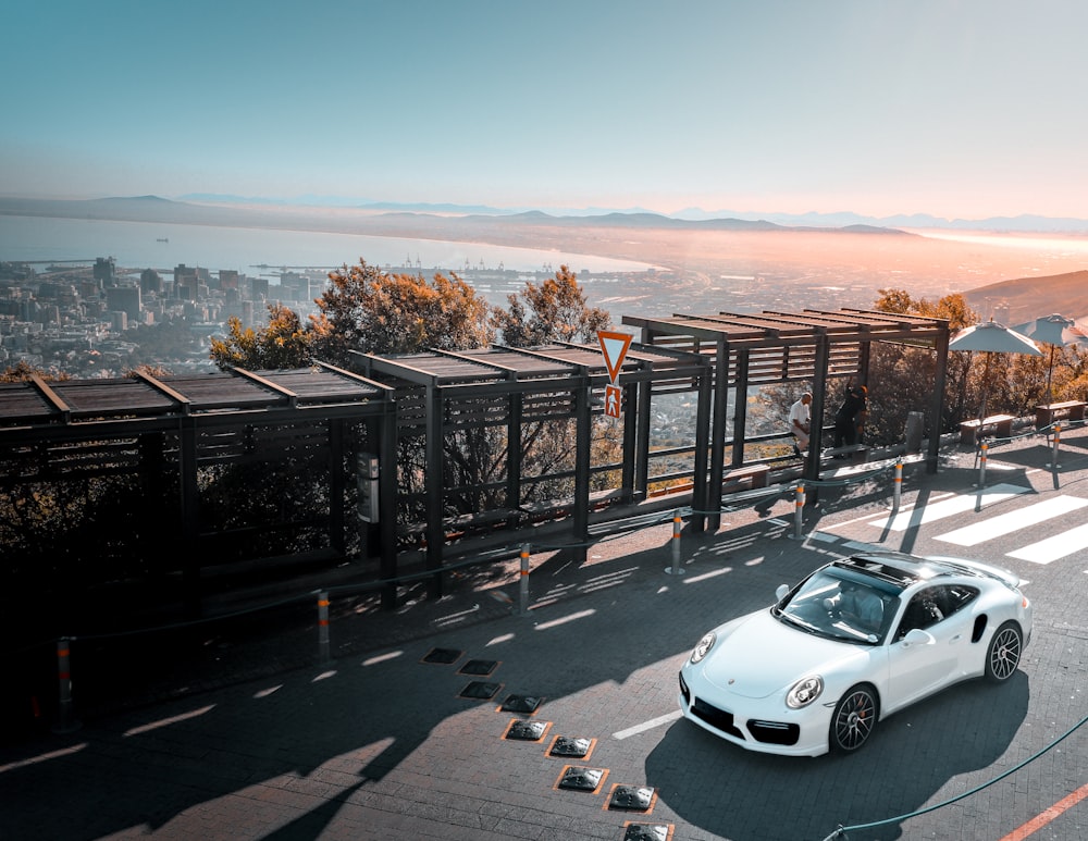 white coupe parking near waiting bench