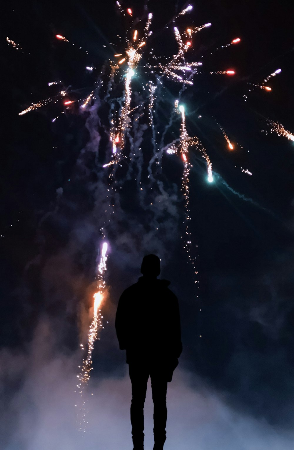 silhouette of man looking at fireworks