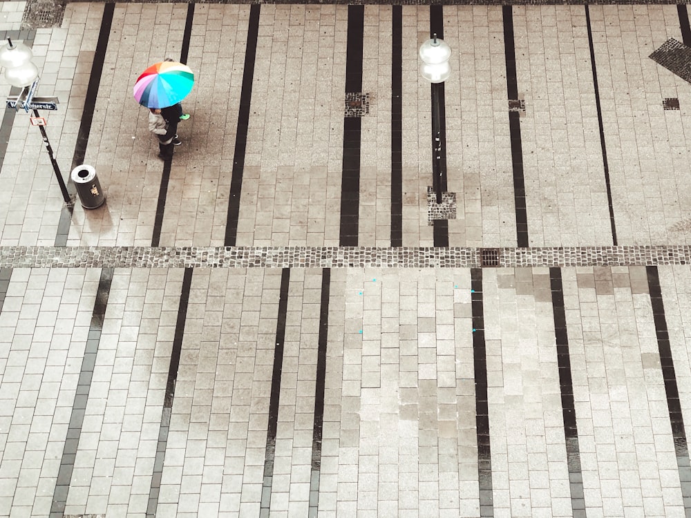 two people walking under rainbow umbrella