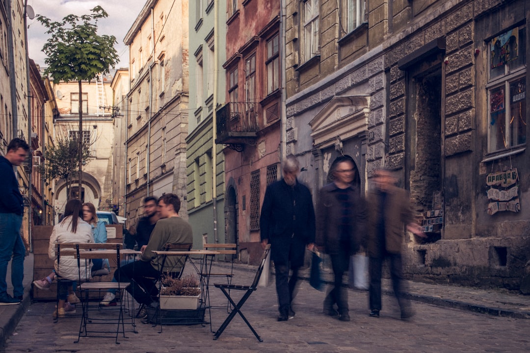 three men walking beside sitting people on alleyway during daytime