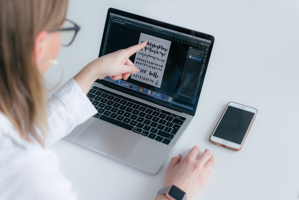 woman pointing MacBook Pro while using Magic Mouse