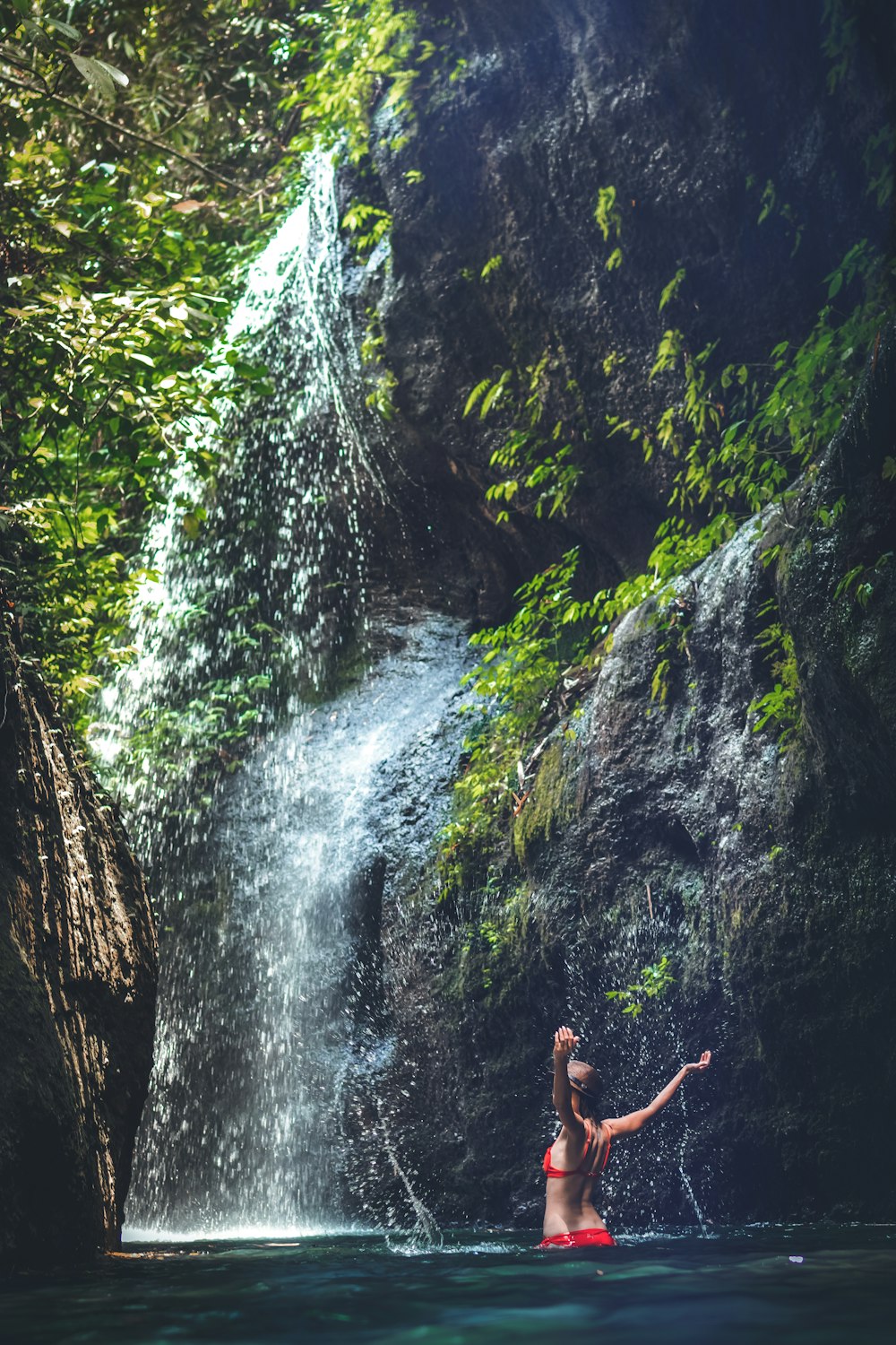 women under a waterfalls during daytime