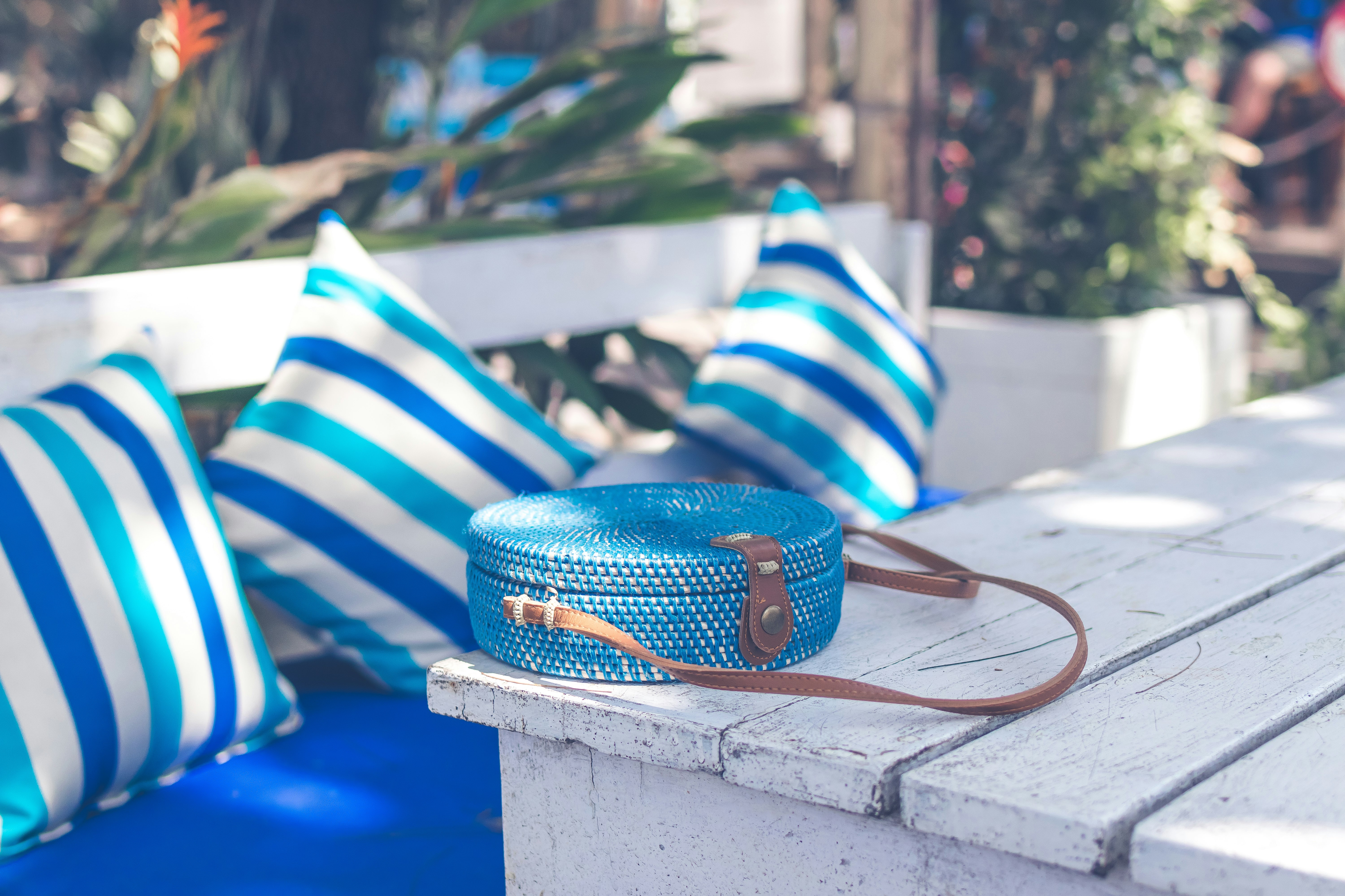 round blue crossbody bag on white table