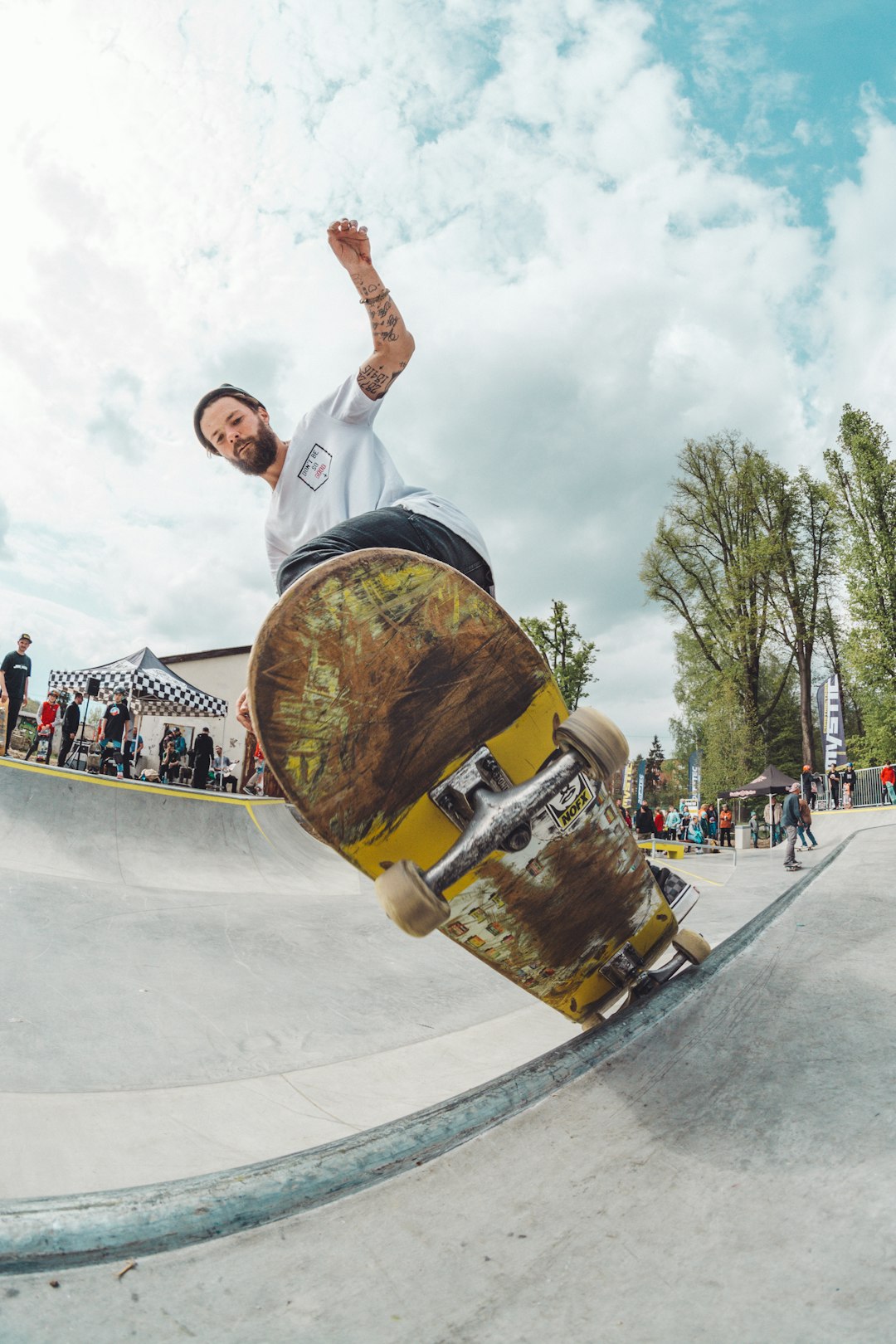 man wearing white shirt doing skateboard trick