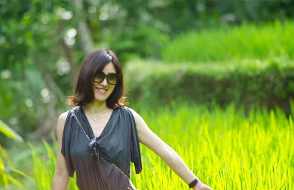 smiling woman standing beside grass field