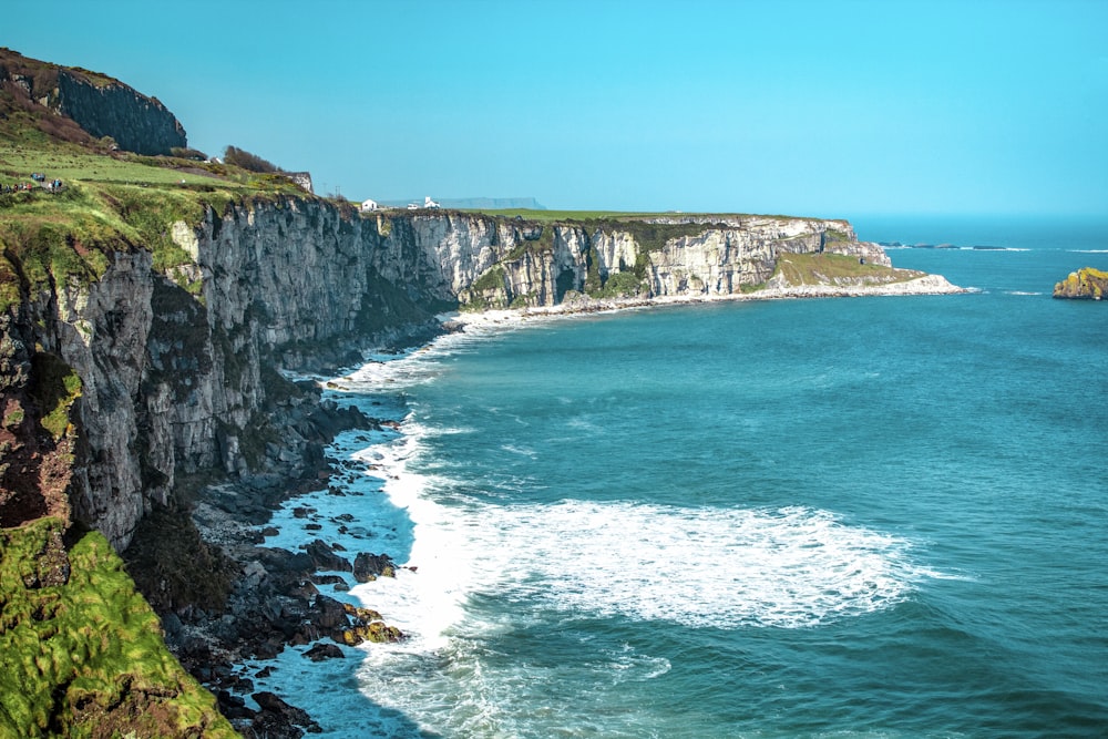 white rock cliff beside body of water'