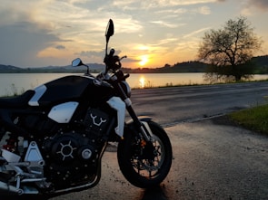 A motorbike parked beside a serene lake in the Scottish Highlands during golden hour.