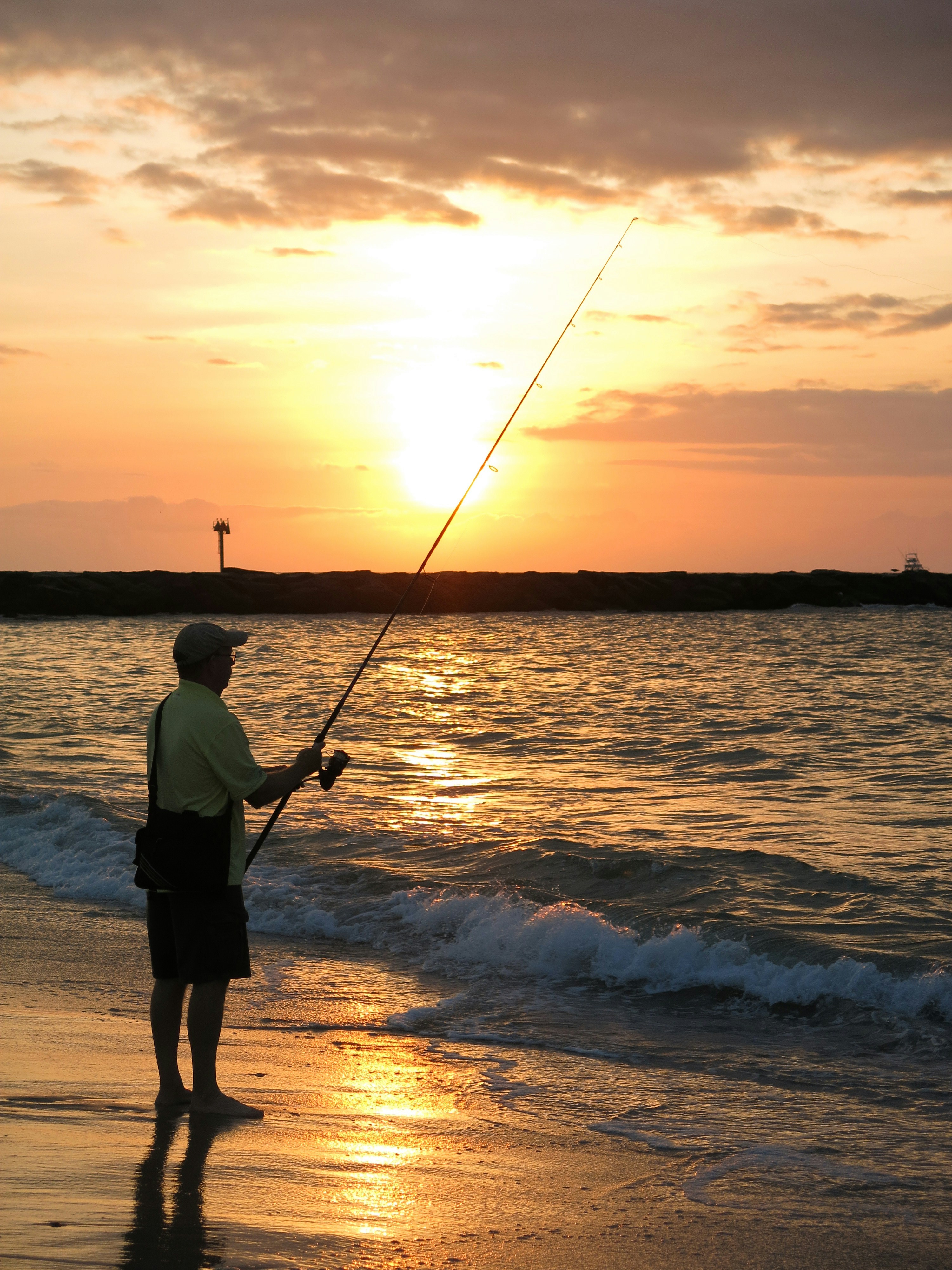 man fishing on shore during golden hour