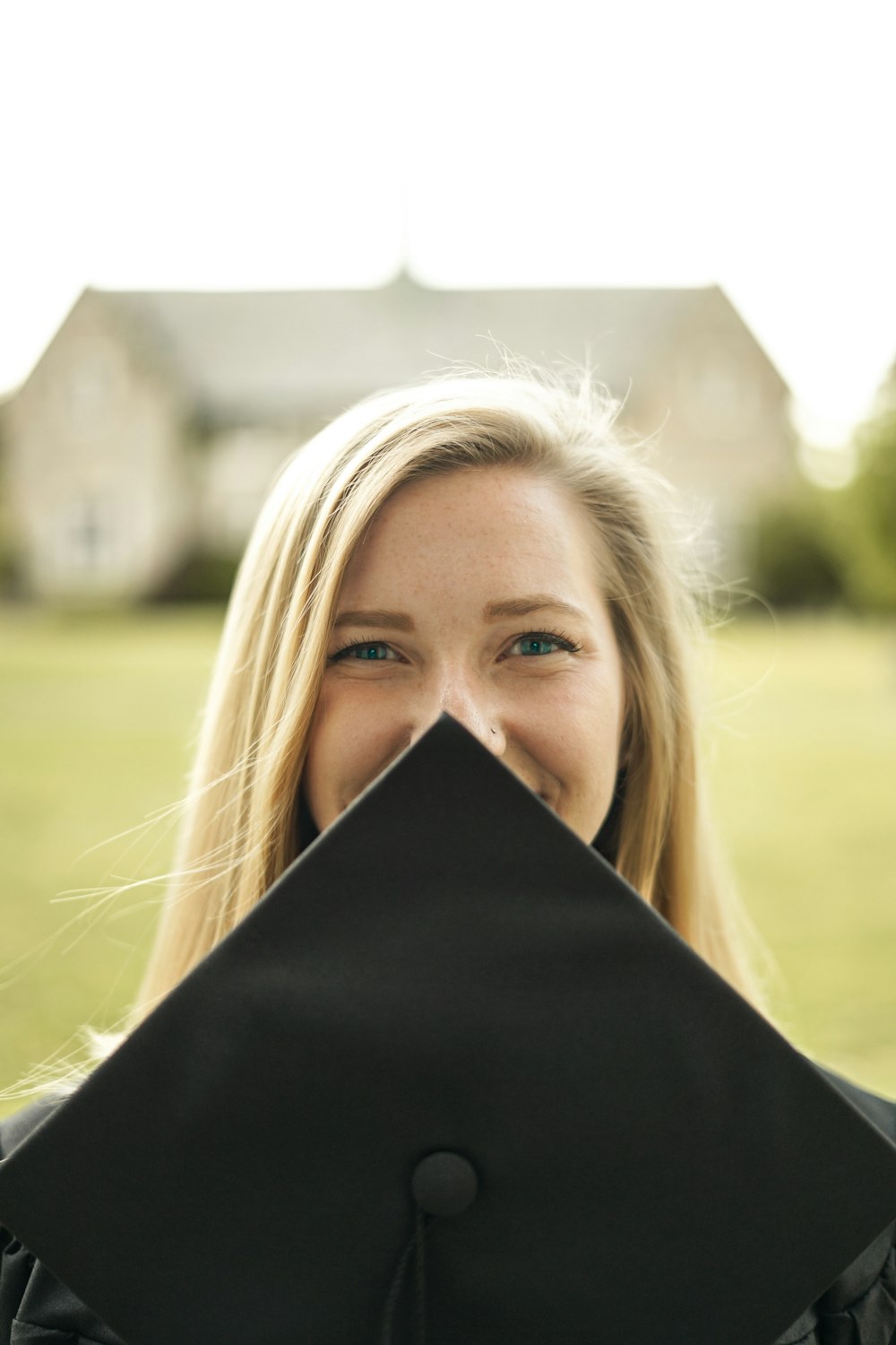 woman covering her face with black mortar board