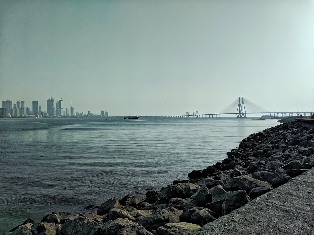 bridge, city, and rocks during day